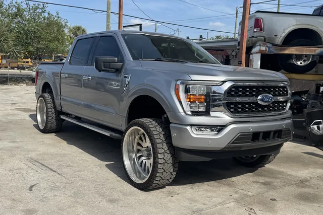 A silver Ford F-150 on a leveling kit and polished wheels outside the shop