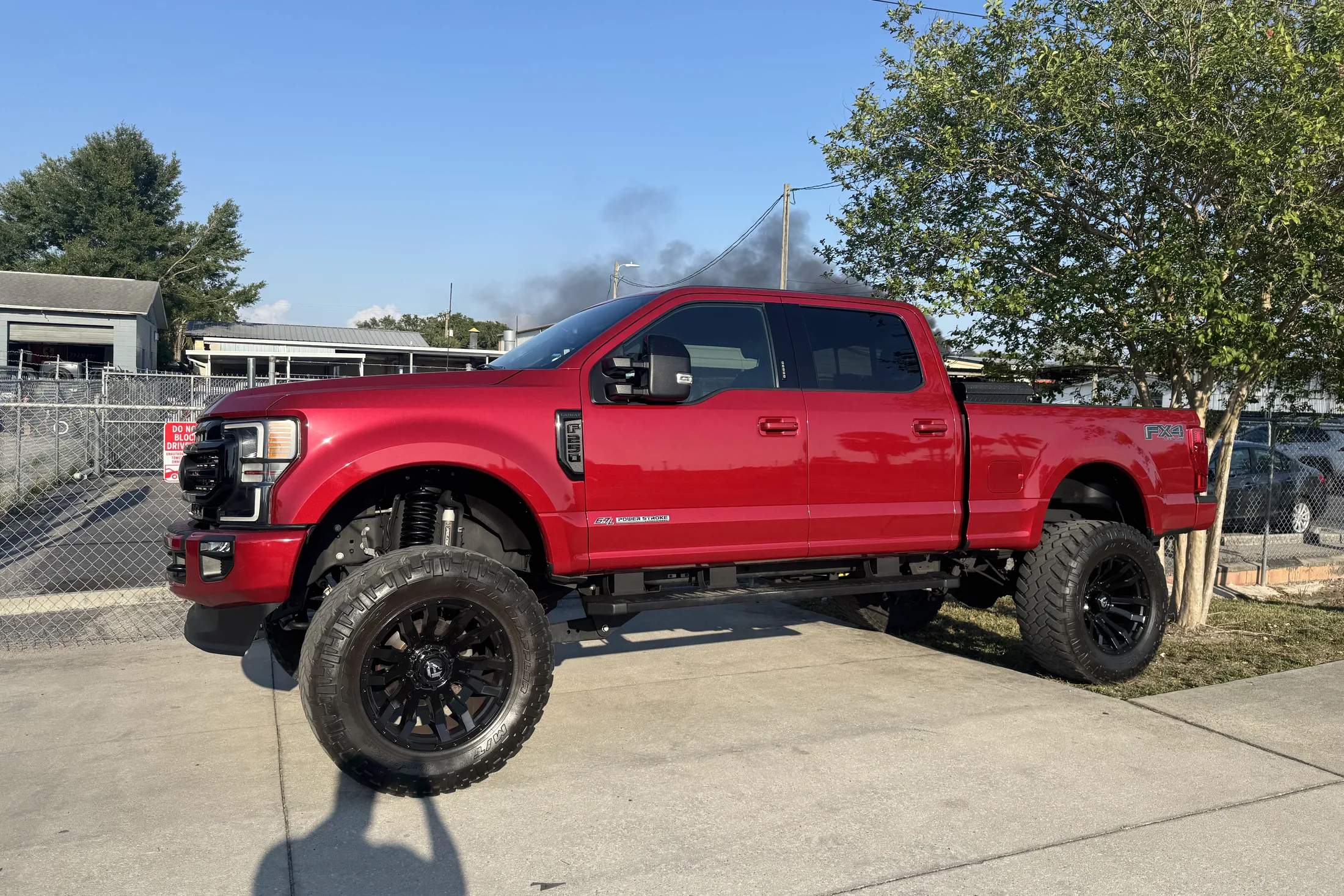 A red Ford Super Duty on a lift kit and black wheels parked outside