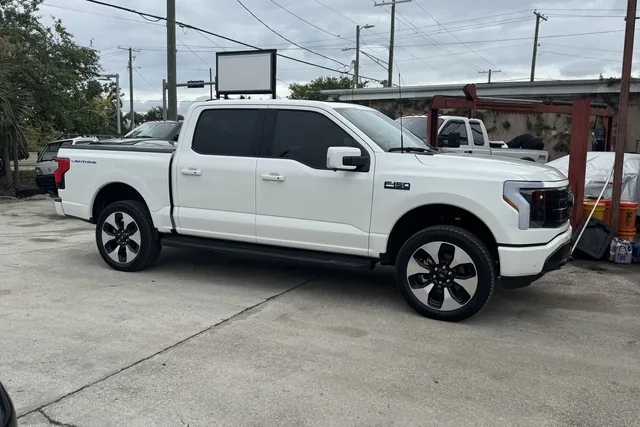 A white Ford F-150 Lightning at stock height on the shop lot