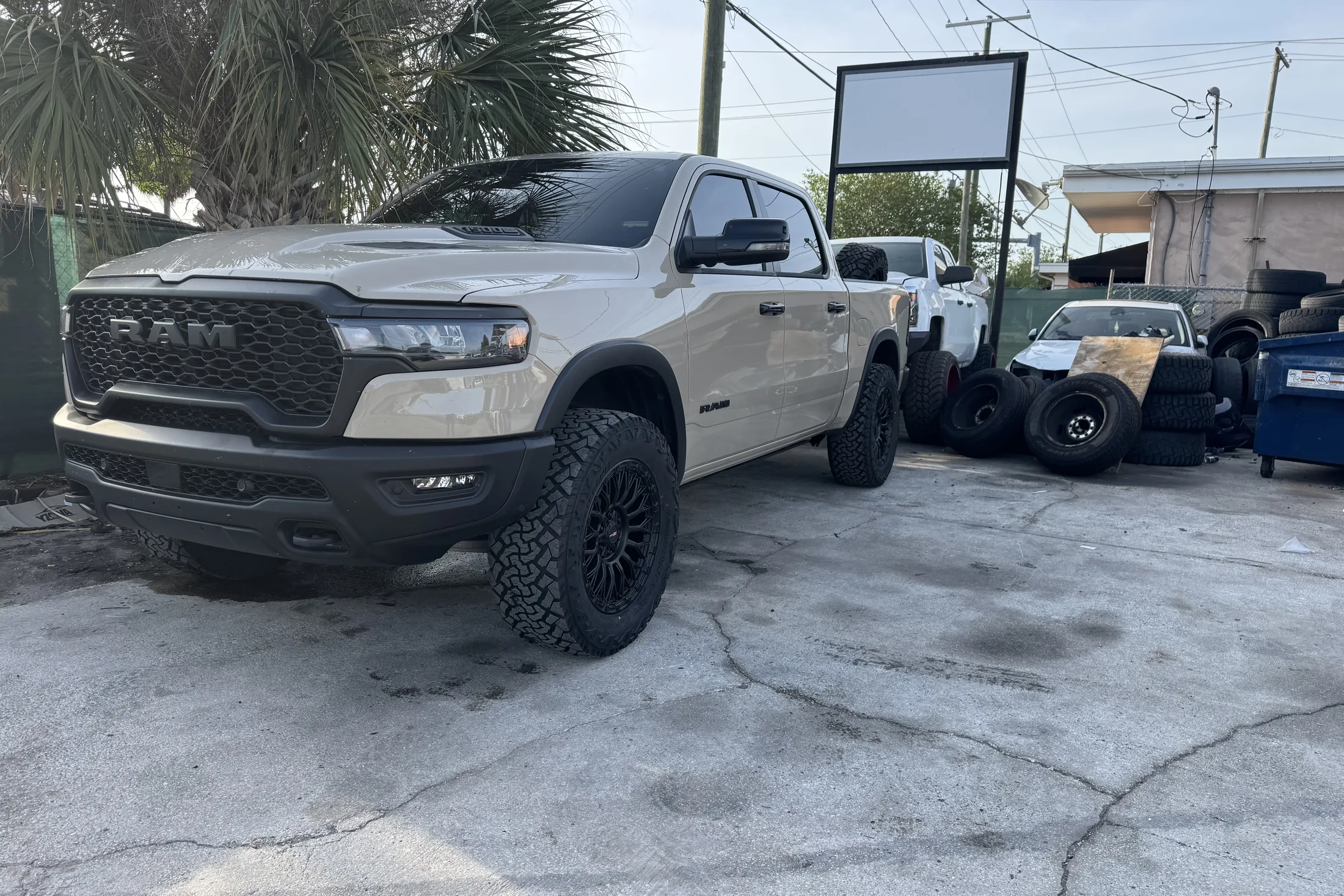 A white Ram 1500 on a leveling kit and black wheels outside the shop