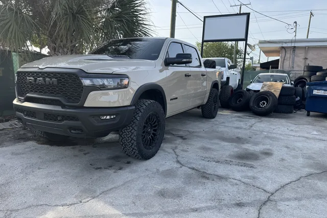 A white Ram 1500 on a leveling kit and black wheels outside the shop