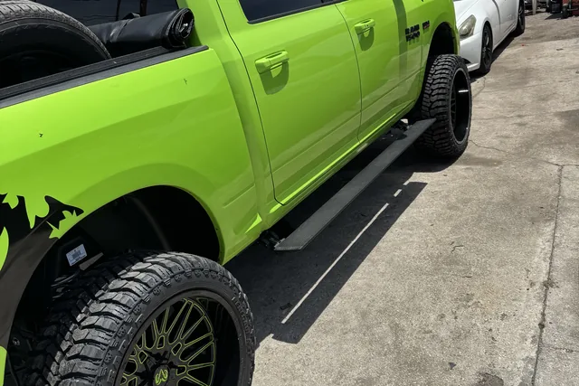 A lime green Ram on a lift kit and matching green wheels outside the bay