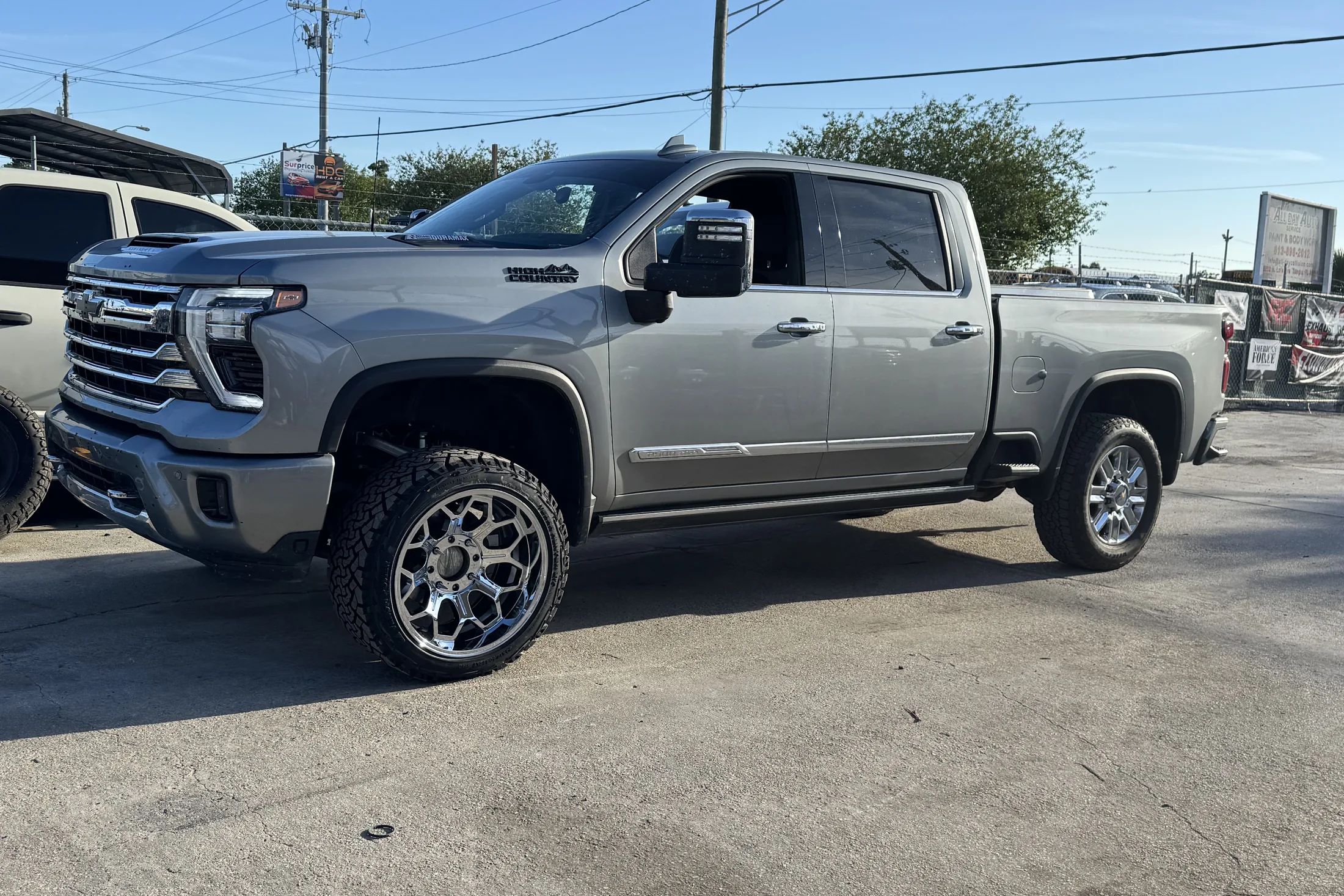 A gray GMC Sierra crew cab on polished wheels outside the shop