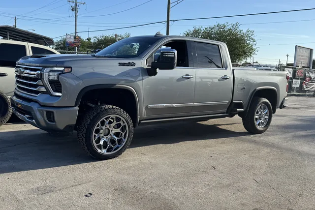 A gray GMC Sierra crew cab on polished wheels outside the shop