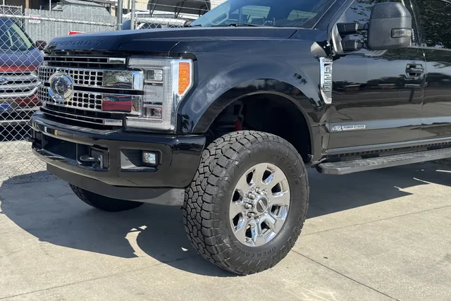 A black Ford F-250 Platinum on a leveling kit with chrome wheels and all-terrain tires