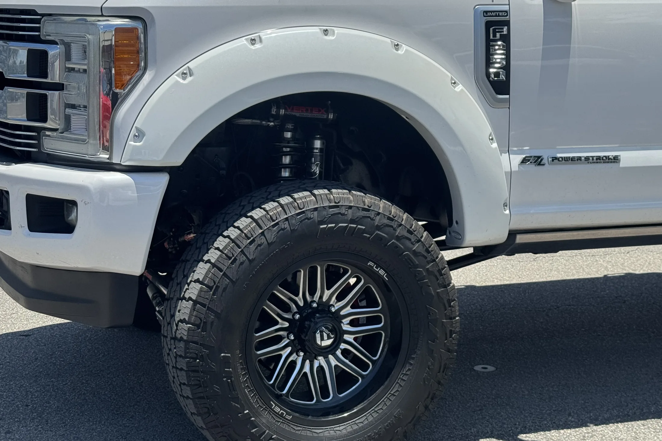 Close-up of a white Ford F-250 fender and front wheel on a black Fuel wheel with an all-terrain tire