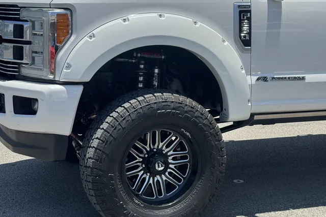 Close-up of a white Ford F-250 fender and front wheel on a black Fuel wheel with an all-terrain tire