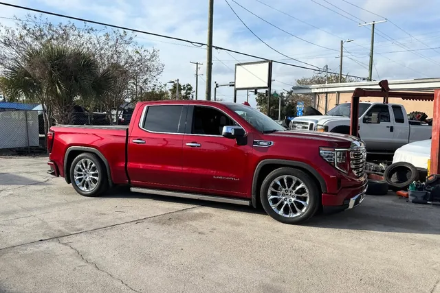 A red GMC Sierra Denali lowered on air bags, sitting low on polished wheels