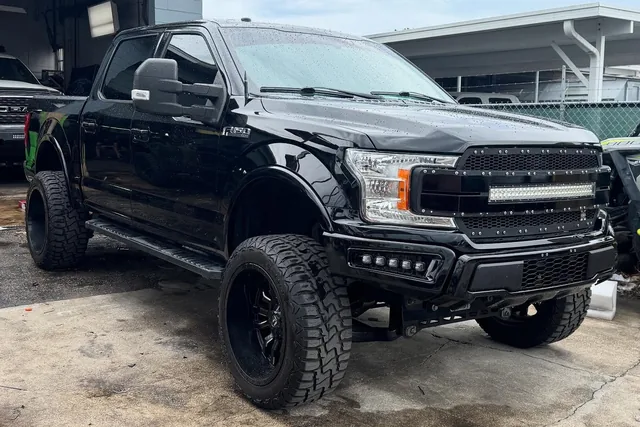 A black Ford F-150 on a six inch lift with a light bar in the grille