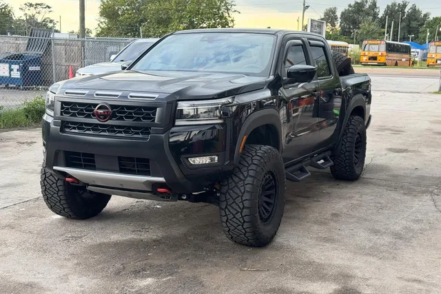 A black Nissan Frontier with a Titan swap, on 33 inch tires
