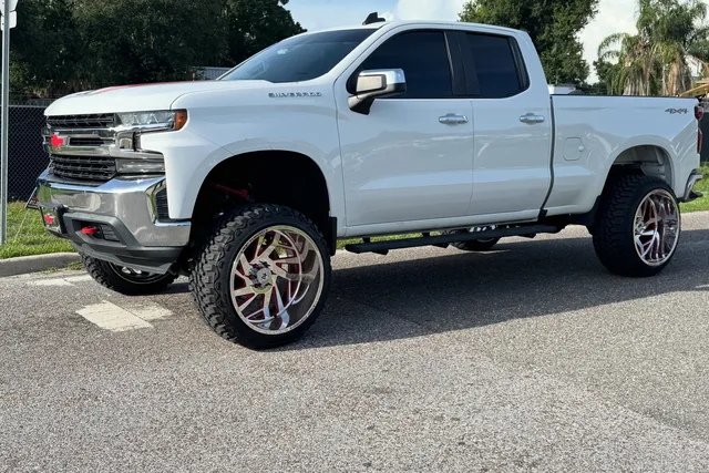 A white Chevy Silverado on an eight inch ReadyLIFT kit with 24 by 14 wheels